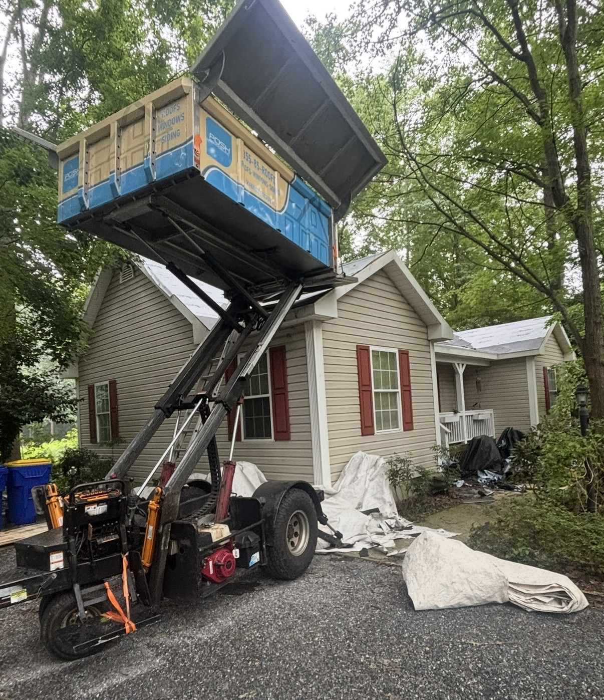 Roofing debris lift positioned beside a home during a roof replacement